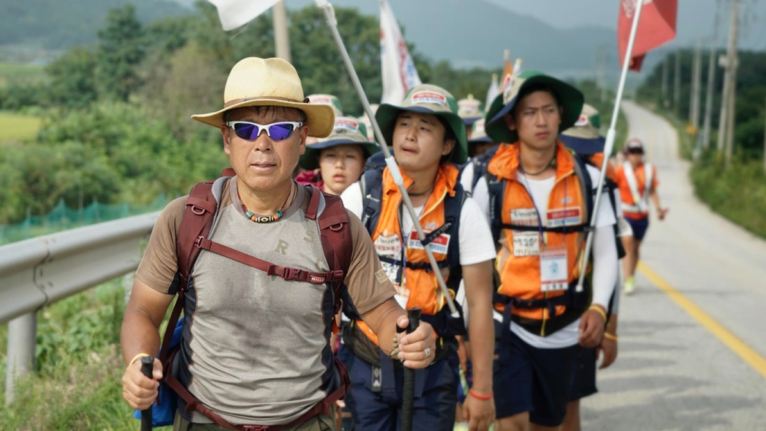 산악 지형을 배경으로 DMZ 평화통일 대장정 참가자들이 행진하는 모습