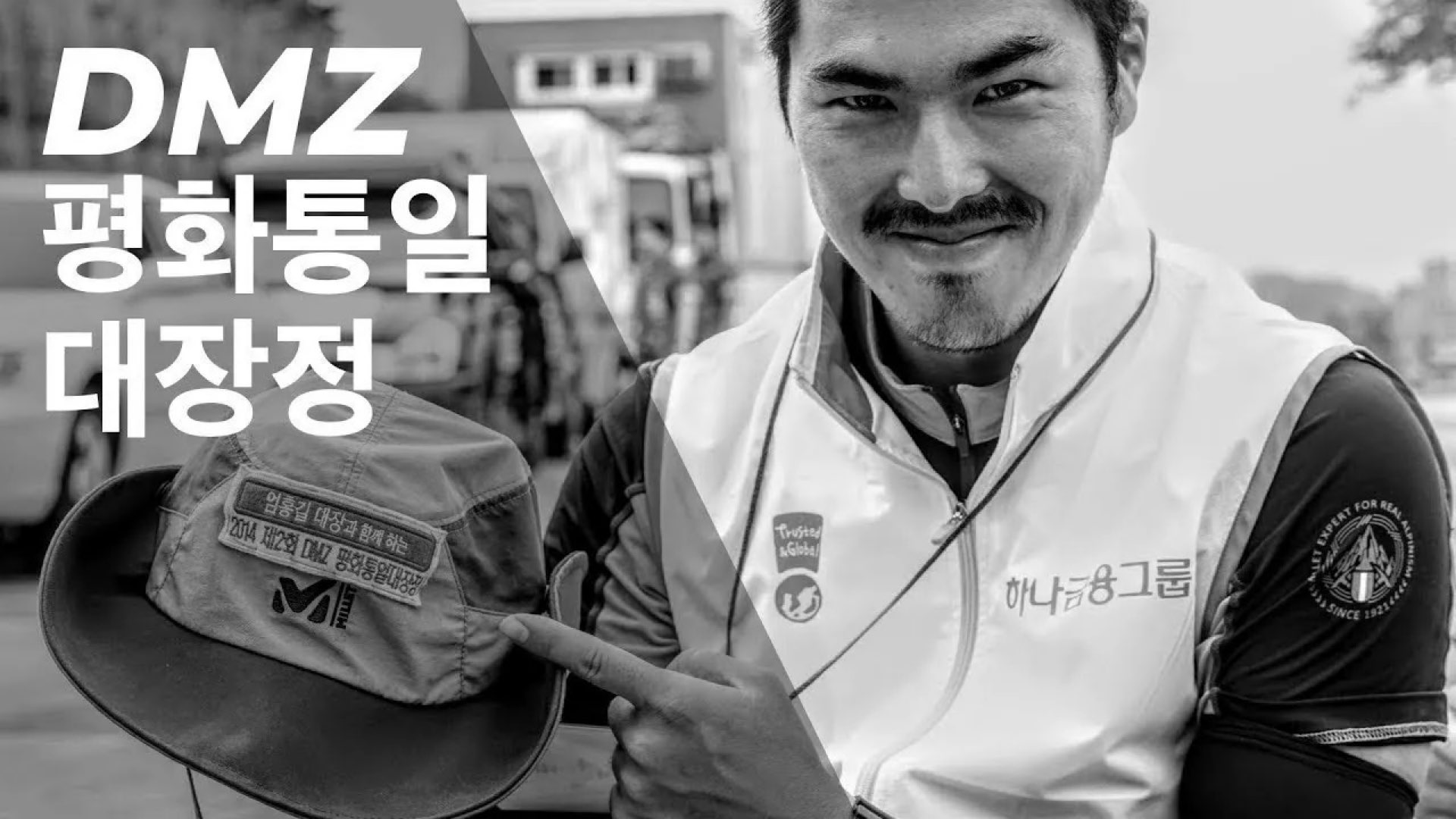 DMZ 평화통일 대장정 참가자가 미소를 지으며 기념품을 들고 있는 흑백 포트레이트 썸네일